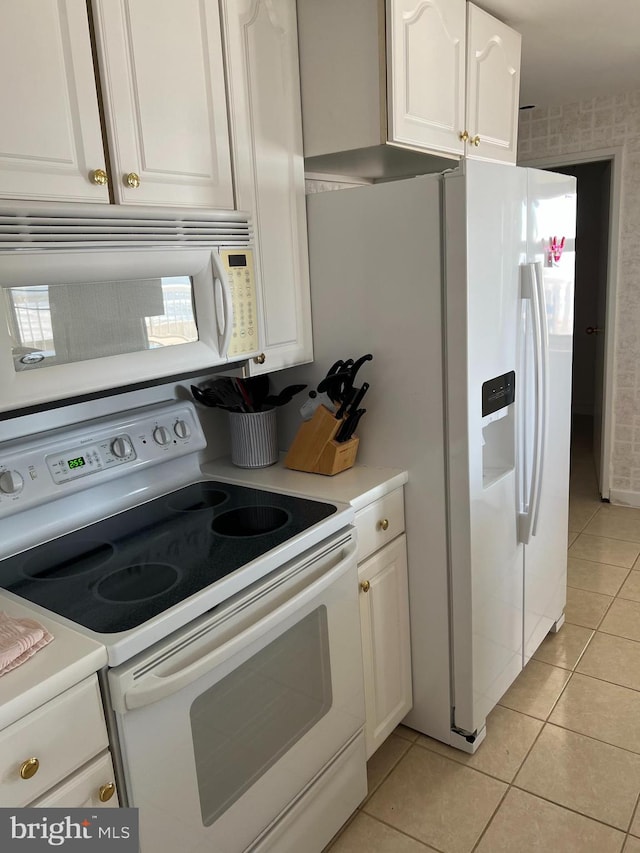 kitchen featuring white cabinets, light tile patterned floors, and white appliances