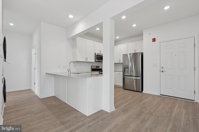 16231 River View Dr, Bristol, PA 19007 - kitchen with stainless steel appliances, light wood-style floors, a peninsula, white cabinets, and a sink