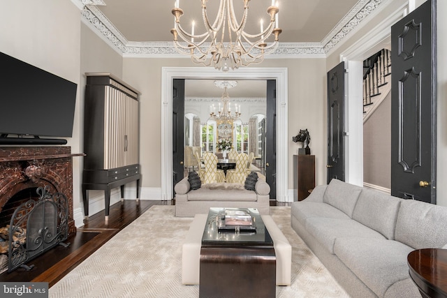 living room with ornamental molding, a fireplace, a chandelier, and hardwood / wood-style floors