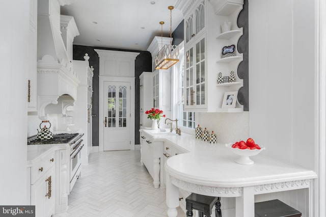 kitchen with high end white range, sink, pendant lighting, and white cabinets