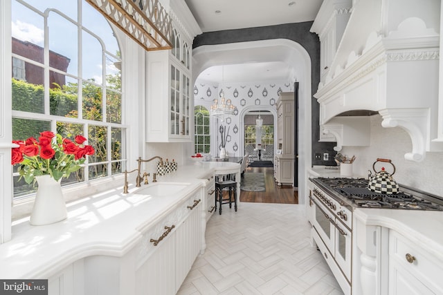 kitchen with white cabinetry, sink, light parquet floors, and range with two ovens