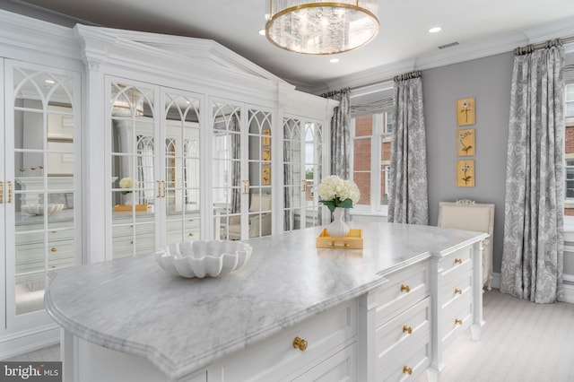 interior space with pendant lighting, a center island, ornamental molding, white cabinets, and french doors