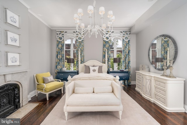 bedroom featuring dark hardwood / wood-style flooring, a notable chandelier, ornamental molding, and a premium fireplace