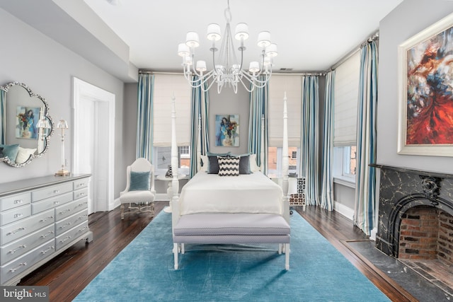 bedroom featuring a fireplace, dark hardwood / wood-style flooring, and a chandelier