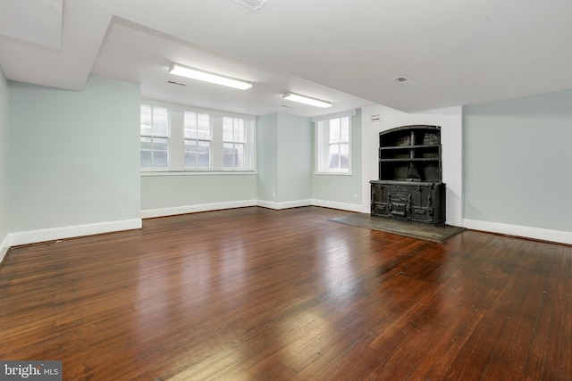 unfurnished living room featuring a wood stove and dark wood-type flooring