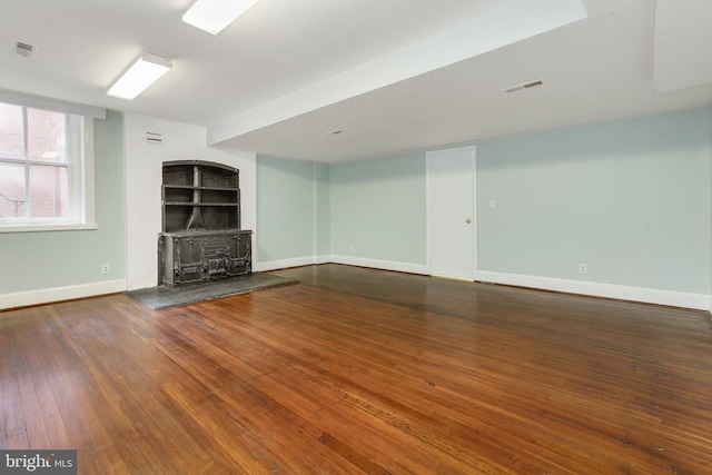 unfurnished living room with dark wood-type flooring and a wood stove