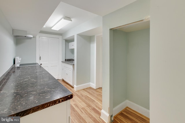 kitchen featuring dark stone counters, range, white cabinetry, and light hardwood / wood-style floors