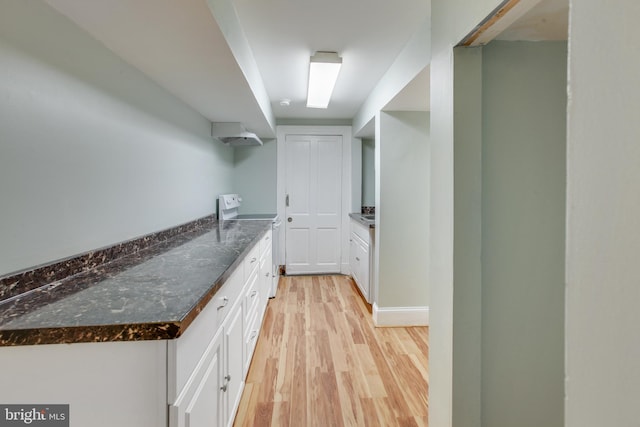 kitchen featuring dark stone counters, white range oven, light hardwood / wood-style floors, and white cabinets