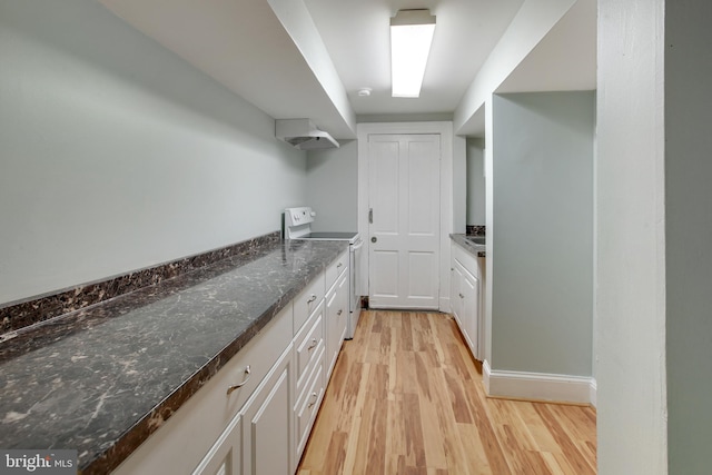 interior space with electric stove, dark stone countertops, light hardwood / wood-style flooring, and white cabinetry