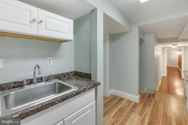 kitchen with white cabinets, light hardwood / wood-style flooring, and sink