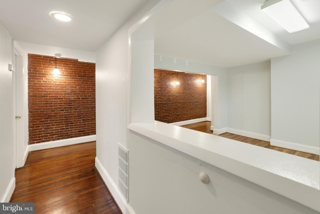 corridor featuring dark hardwood / wood-style flooring and brick wall