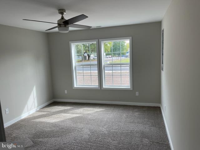 carpeted spare room featuring ceiling fan