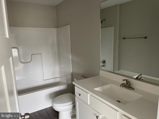 full bathroom with hardwood / wood-style flooring, vanity, toilet, and shower / tub combination