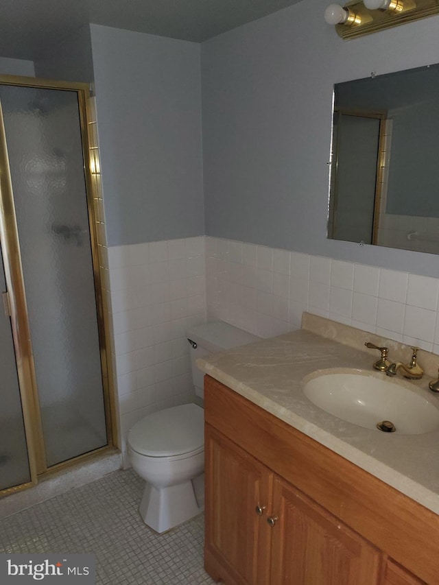 bathroom with tile walls, walk in shower, toilet, vanity with extensive cabinet space, and tile flooring