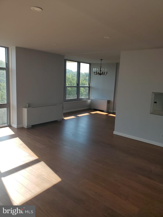 empty room with dark hardwood / wood-style flooring and a chandelier