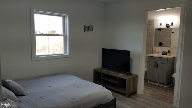 bedroom with hardwood / wood-style floors, multiple windows, and ensuite bathroom