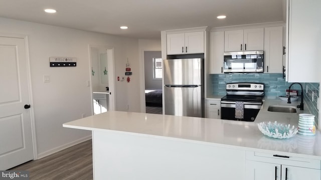 kitchen featuring appliances with stainless steel finishes, white cabinetry, dark hardwood / wood-style floors, and tasteful backsplash