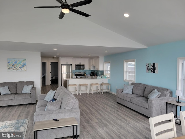 living room featuring ceiling fan, sink, high vaulted ceiling, and light hardwood / wood-style floors