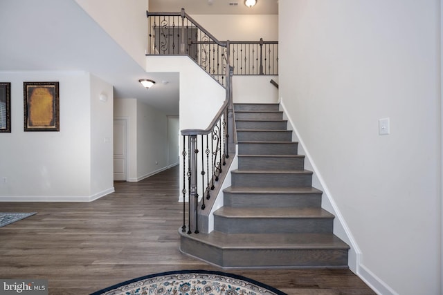 stairs featuring a towering ceiling and hardwood / wood-style flooring