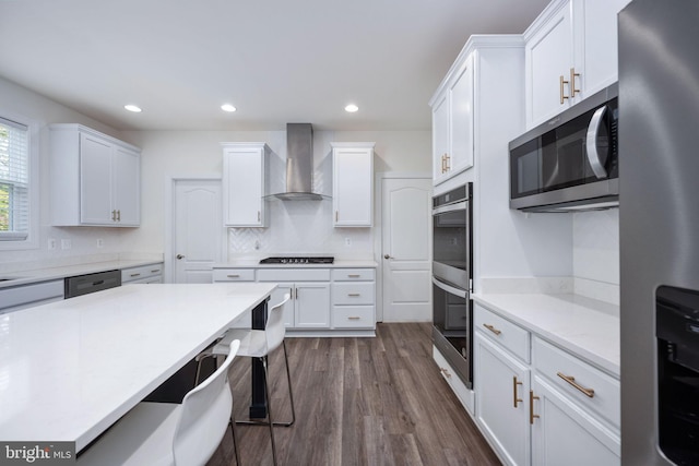 kitchen featuring backsplash, dark hardwood / wood-style flooring, white cabinetry, wall chimney exhaust hood, and stainless steel appliances