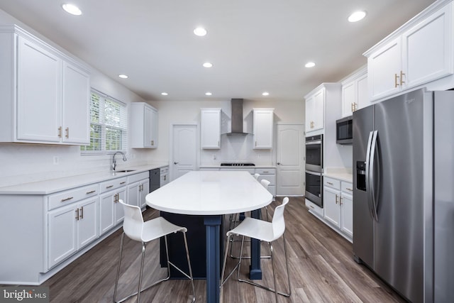 kitchen featuring appliances with stainless steel finishes, wall chimney exhaust hood, white cabinetry, and sink