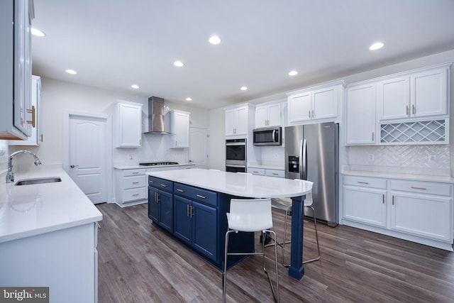 kitchen with sink, appliances with stainless steel finishes, wall chimney range hood, and white cabinets