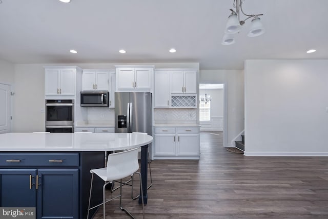 kitchen with white cabinetry, stainless steel appliances, dark hardwood / wood-style flooring, and pendant lighting