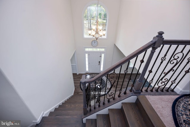 staircase with hardwood / wood-style floors, a chandelier, and a high ceiling