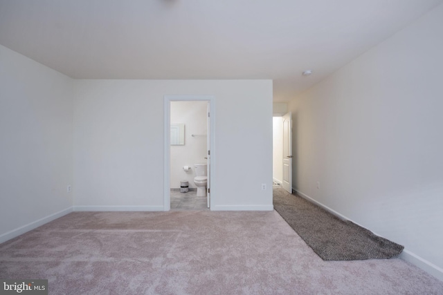 unfurnished bedroom featuring connected bathroom and light carpet