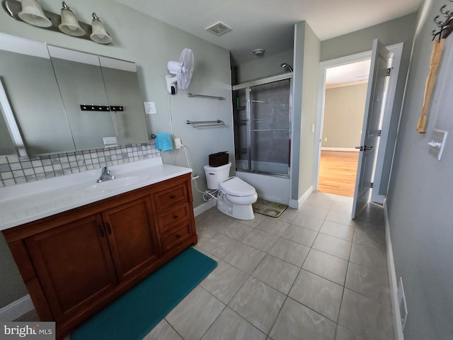 full bathroom featuring vanity, tile floors, toilet, shower / bath combination with glass door, and tasteful backsplash