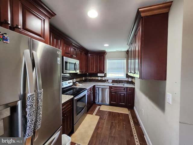 kitchen with appliances with stainless steel finishes, tasteful backsplash, light stone counters, sink, and dark hardwood / wood-style floors