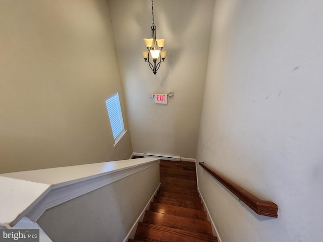 stairway featuring dark hardwood / wood-style flooring, a baseboard heating unit, and a chandelier