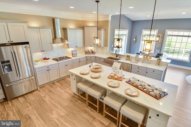 kitchen featuring wall chimney range hood, plenty of natural light, stainless steel appliances, and sink