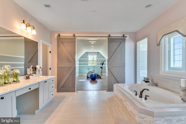 bathroom with tiled bath, lofted ceiling, tile flooring, and vanity