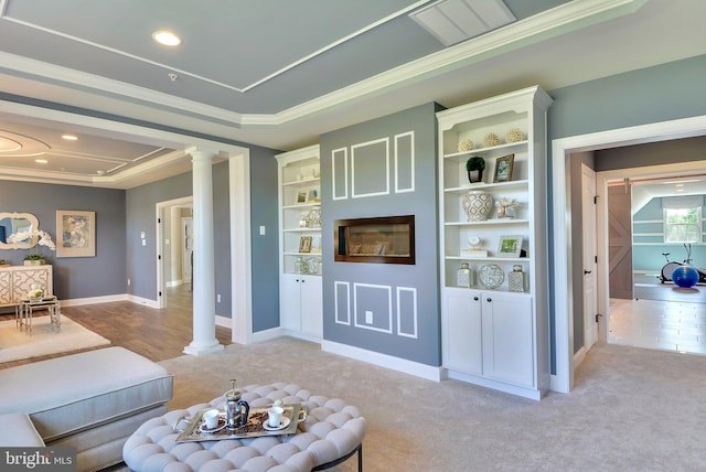 living room featuring decorative columns, a raised ceiling, light tile floors, and built in shelves