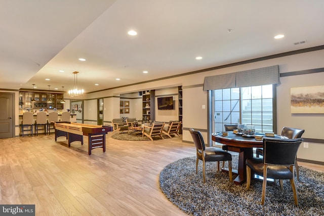 dining room featuring a chandelier, light hardwood / wood-style floors, and crown molding