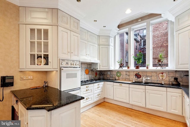 kitchen featuring sink, white cabinets, dark stone countertops, backsplash, and light hardwood / wood-style floors