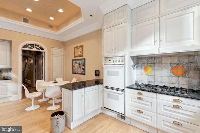 kitchen with backsplash, double oven, and white cabinetry