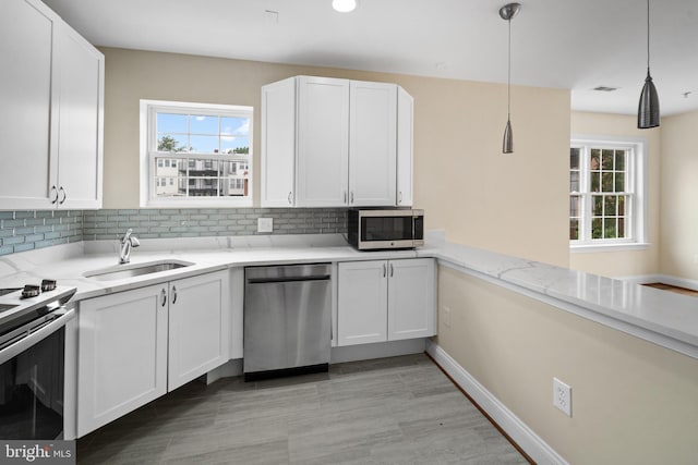 kitchen with decorative light fixtures, appliances with stainless steel finishes, white cabinets, backsplash, and sink