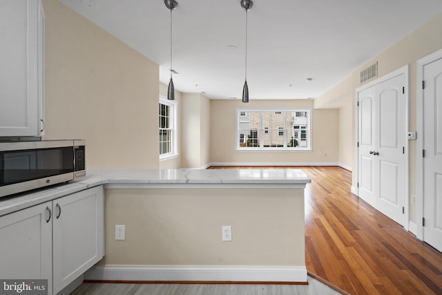 kitchen featuring white cabinets, pendant lighting, and kitchen peninsula