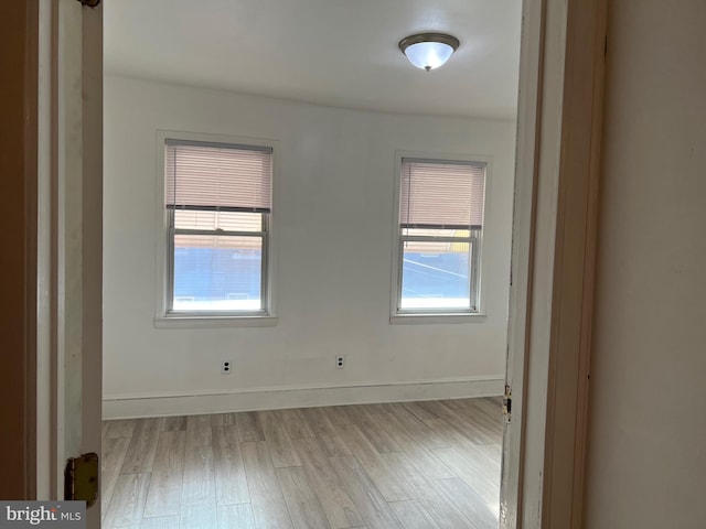 empty room with plenty of natural light and light hardwood / wood-style flooring