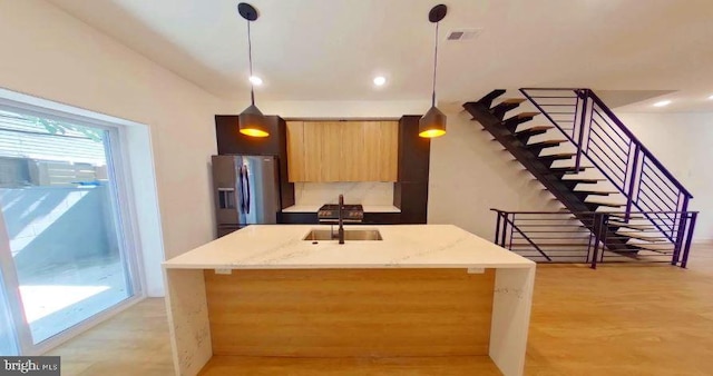 kitchen with hanging light fixtures, a healthy amount of sunlight, and stainless steel fridge