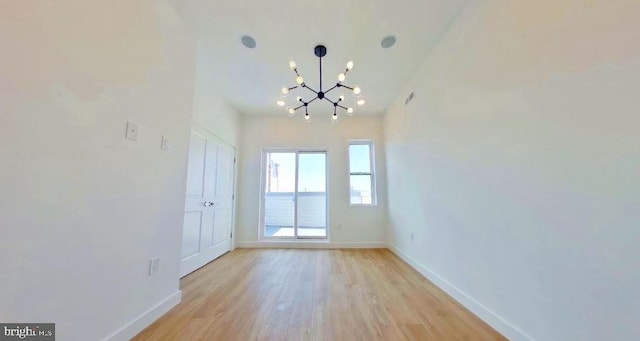 unfurnished room featuring light hardwood / wood-style flooring and a chandelier