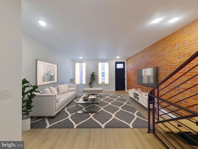 living room with brick wall and light hardwood / wood-style flooring