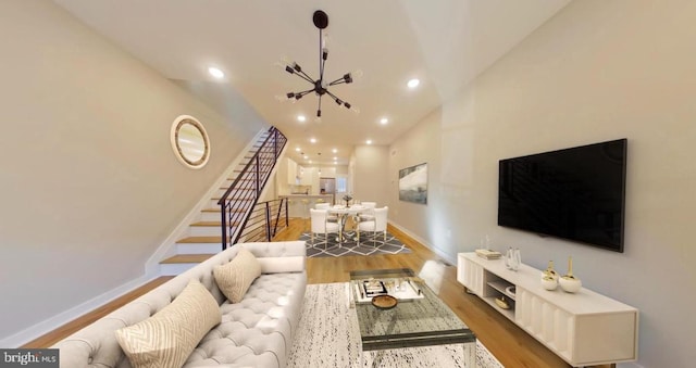 living room with hardwood / wood-style floors, a notable chandelier, and high vaulted ceiling