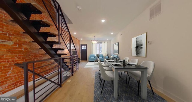 dining room featuring light hardwood / wood-style flooring and brick wall