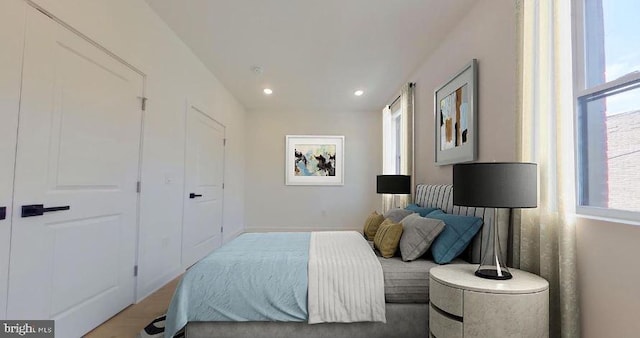 bedroom with light hardwood / wood-style floors and multiple windows