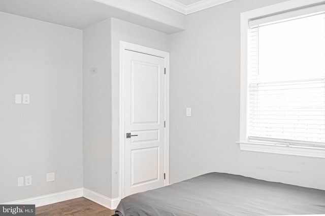 unfurnished bedroom with dark hardwood / wood-style floors and ornamental molding