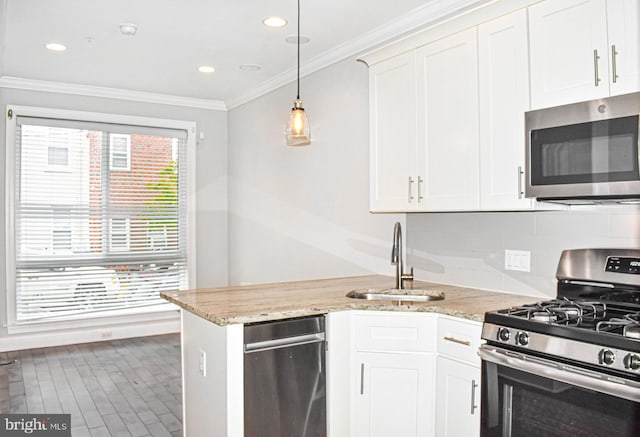 kitchen featuring pendant lighting, sink, white cabinets, backsplash, and stainless steel appliances