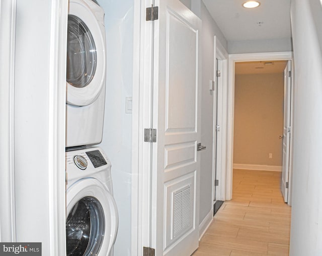 washroom with light hardwood / wood-style floors and stacked washing maching and dryer